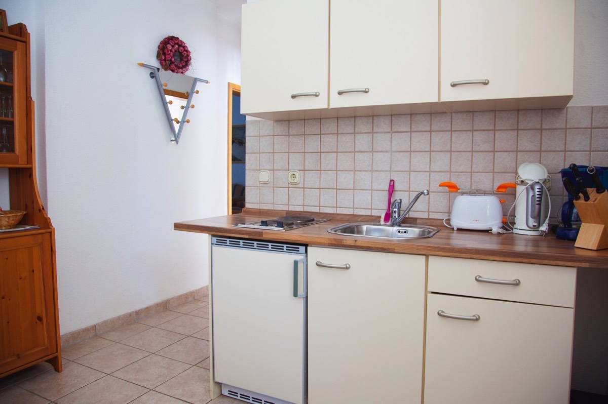 Offene Küchenzeile der Wohnung 1 mit Ceranfeld und Kühlschrank