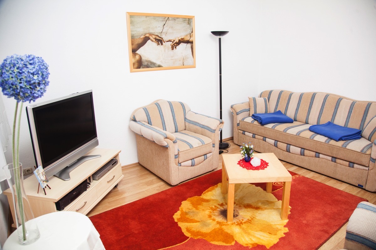 Blick in den Wohnbereich der Wohnung 1 mit Couchgarnitur und Esstisch