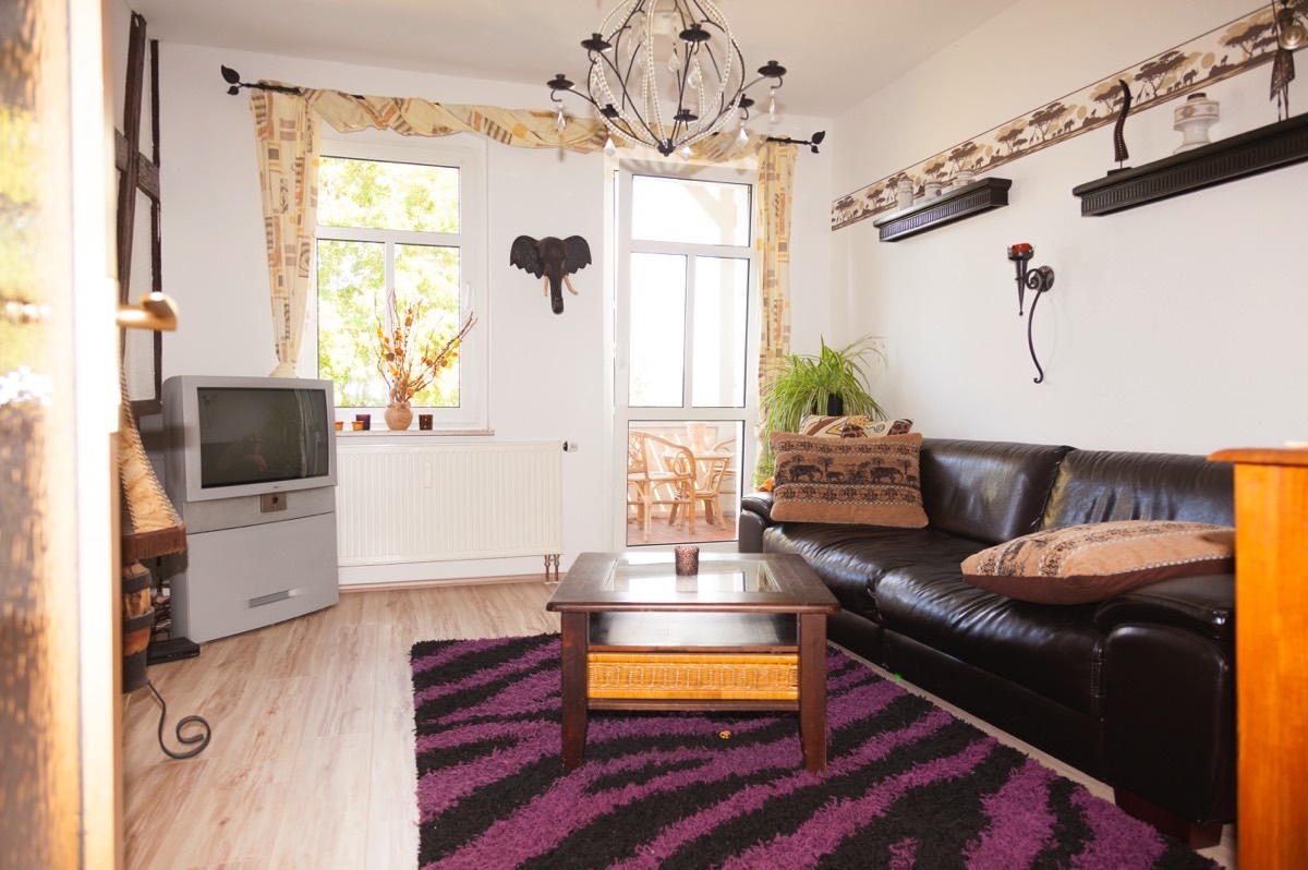 Wohnraum der Wohnung 2 mit Ledersofa und Zugang zum Balkon