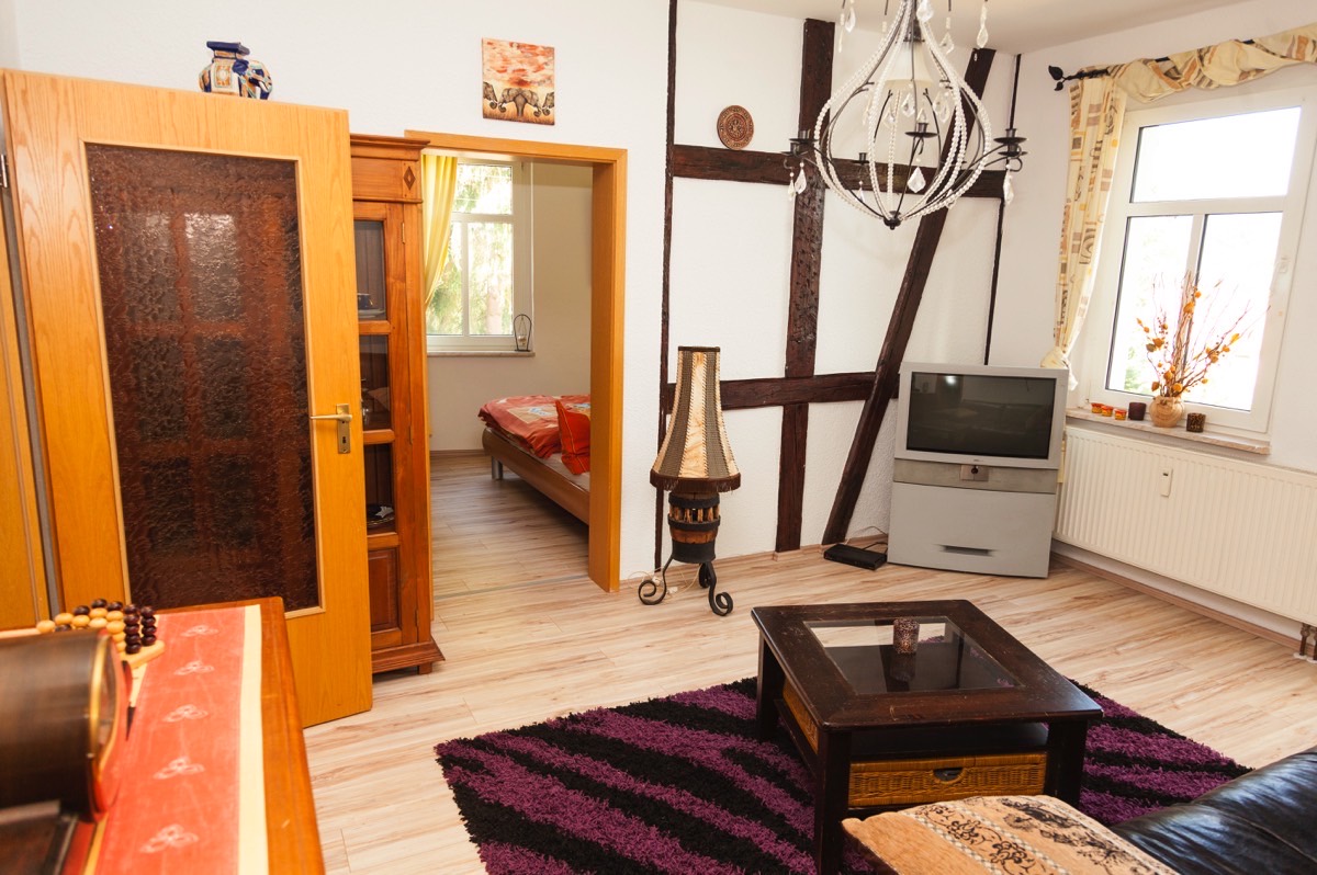 Wohnraum der Wohnung 2 mit sichtbarem Fachwerk und Blick zum Schlafraum